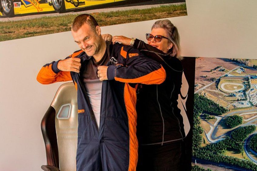 Une personne portant une combinaison intégrale aux couleurs orange et noire, debout à côté d’une chaise. 3