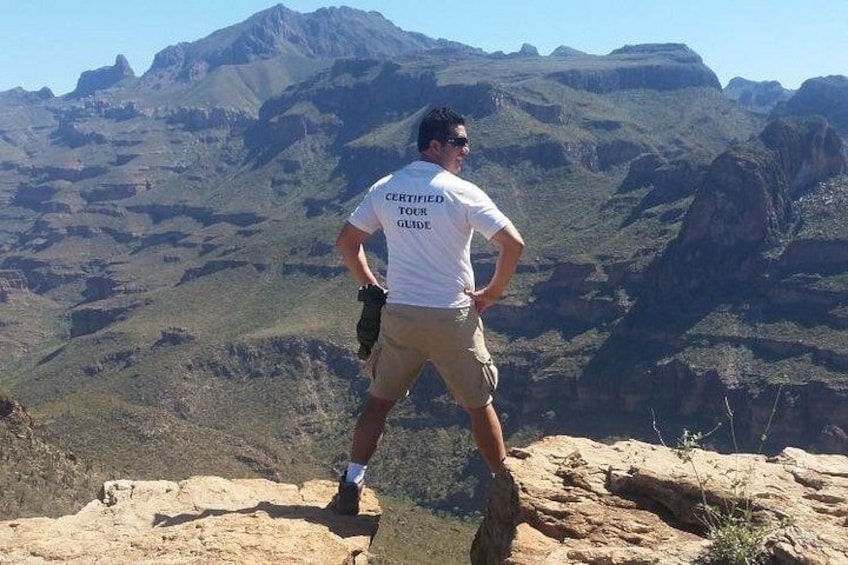 A person standing on a rocky outcrop with a mountainous landscape in the background. 3