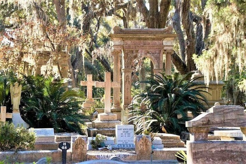 A cemetery with headstones, a central archway, and lush greenery. 3