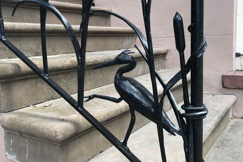 Een leuning van een zwarte metalen trap met een vogelmotief. 3