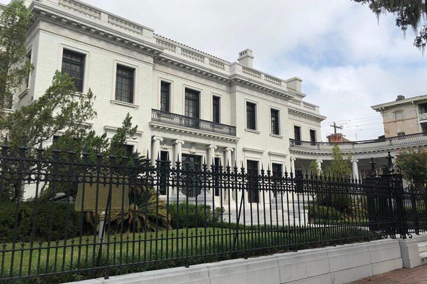 A large, white building with columns and a black fence in front. 4