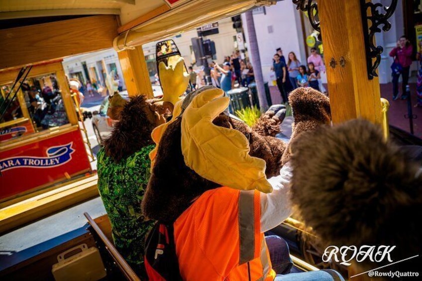 Een rode bagagewagen met de tekst 'SARA TROLLEY', met passagiers die dierenoren dragen. 2