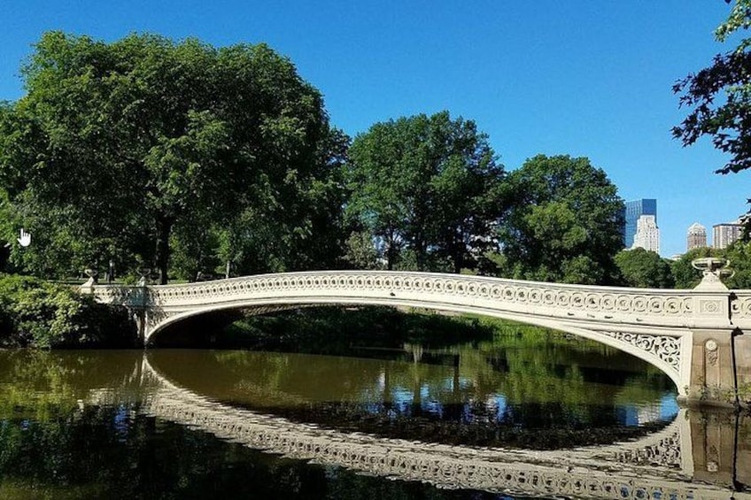 Un pont de pierre enjambant une rivière paisible, entouré d’arbres verdoyants et sous un ciel bleu clair. 3
