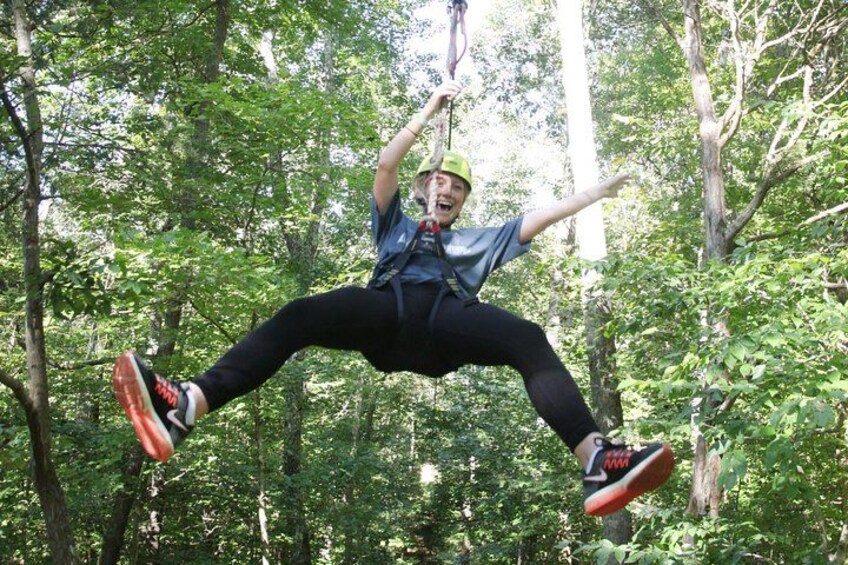 Una persona en pleno vuelo sobre una tirolesa en un bosque. 3