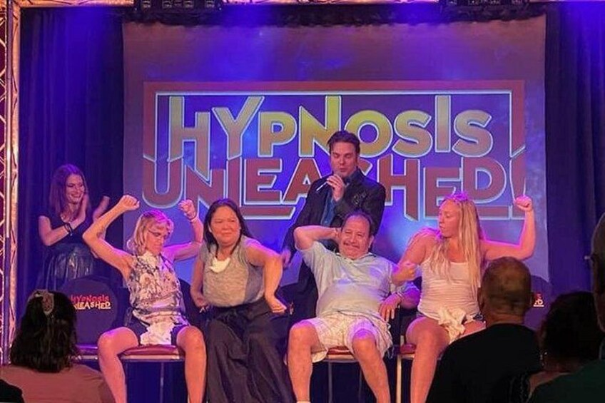 Un grupo de personas en el escenario con un cartel que dice 'HYPNOSIS UNLEASHED'. 4
