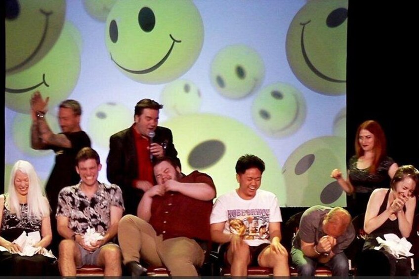 Un grupo de personas en el escenario frente a un fondo con caras sonrientes. 2