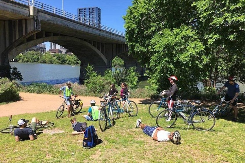 Eine Gruppe Radfahrer macht eine Pause in Flussnähe unter einer Brücke. 1