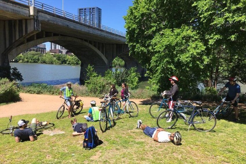 Des cyclistes se reposent sous un pont, près d’une rivière. 1