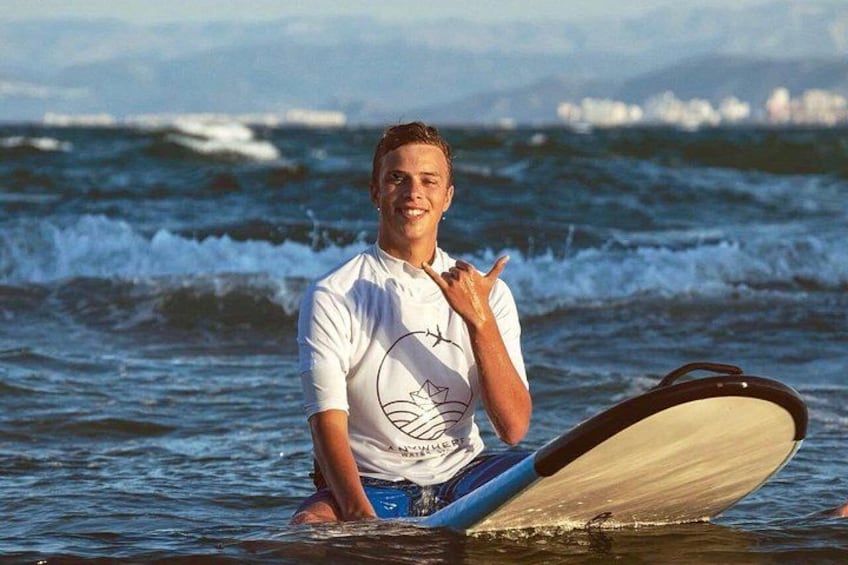 A person sitting on a surfboard in the ocean with waves in the background. 5