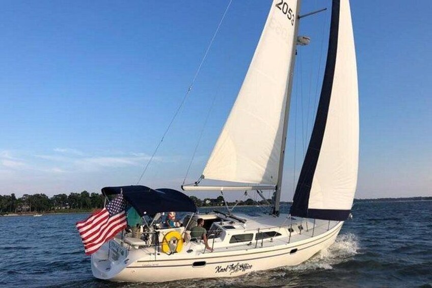 En segelbåt med en amerikansk flagga, segel och en hytt där människor befinner sig på däck. 4
