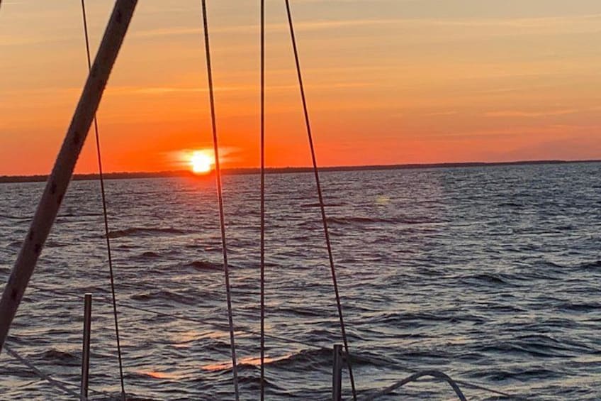Solnedgang over havet med en båds mast i forgrunden. 3