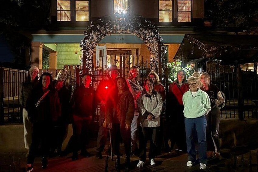 Un grupo de personas de pie frente a un edificio con un arco decorativo. 2