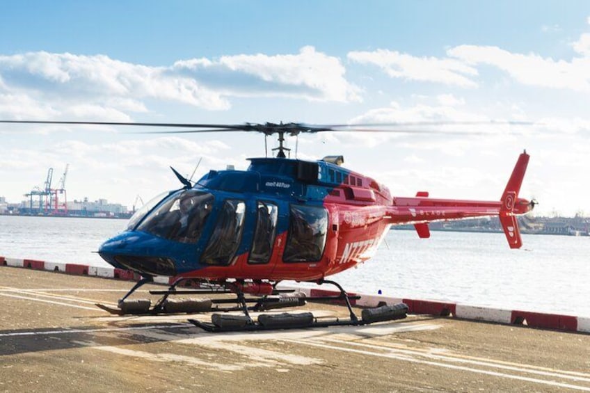 En röd och blå helikopter stod parkerad på en brygga vid vattnet. 2