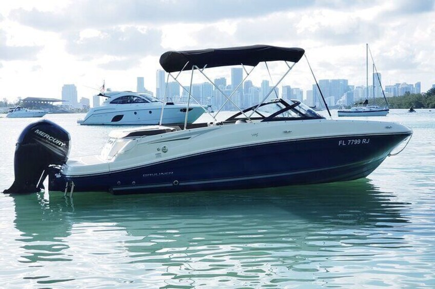 A motorboat named FL 7799 RJ docked in a marina with other boats and a city skyline in the background. 4