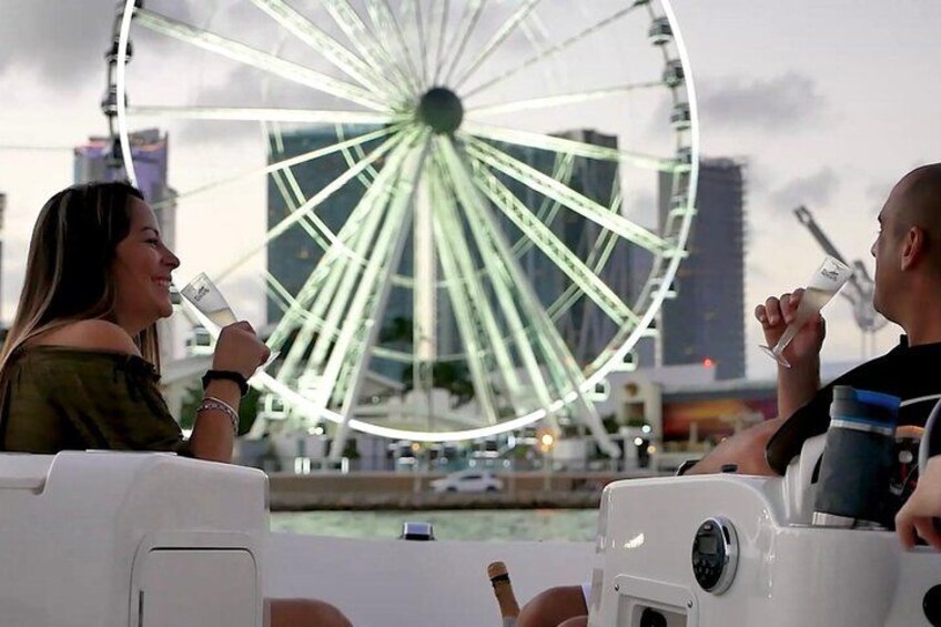 Two people sitting on a boat, a Ferris wheel in the background, and a cityscape. 5