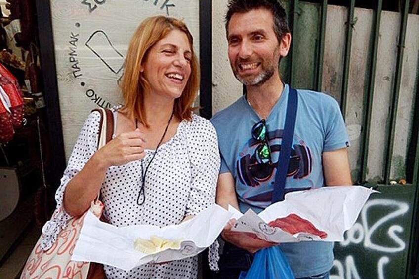 Two people holding shopping bags, standing in front of a wall with graffiti. 3
