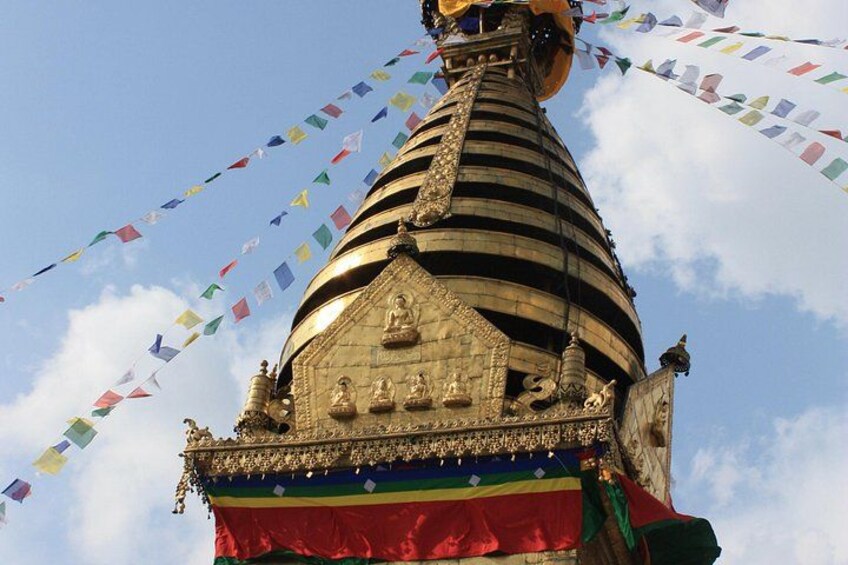 A large, ornate stupa with intricate carvings and a flag at its base. 1