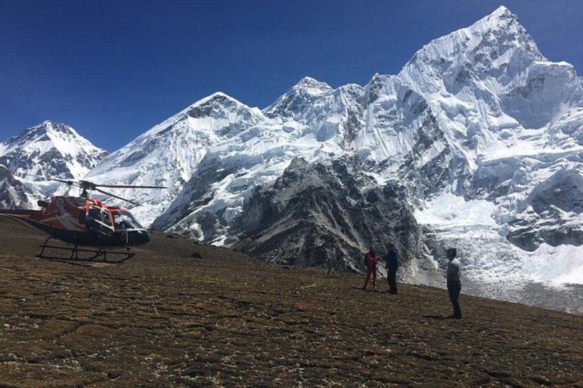Un helicóptero sobre terreno rocoso, con montañas nevadas al fondo. 1