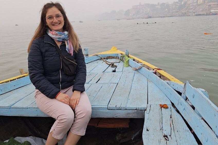 A person sitting on a wooden boat with a river in the background. 4