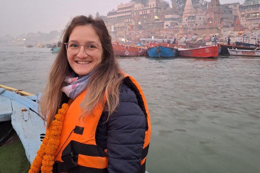 A person standing by a river with boats and buildings in the background. 3