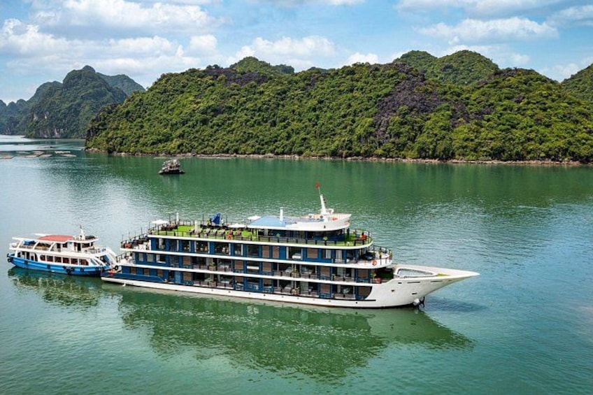 A large river cruise ship with multiple decks, surrounded by lush green hills and a clear blue sky. 1