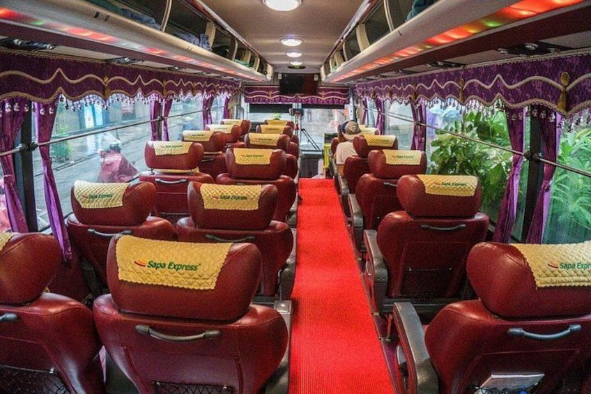 Interior de un tren con asientos rojos, una alfombra roja y cortinas moradas. 1