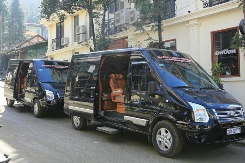 A black van with its door open, parked on a street with buildings in the background. 2