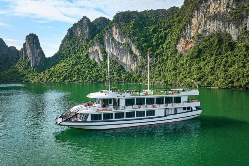 A white boat with a blue stripe on a green river surrounded by cliffs. 4