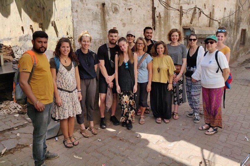 A group of people standing in an outdoor setting with a wall and some vegetation in the background. 2