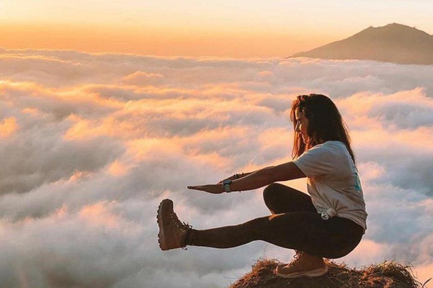 A person sitting on a rock with a mountain in the background. 1