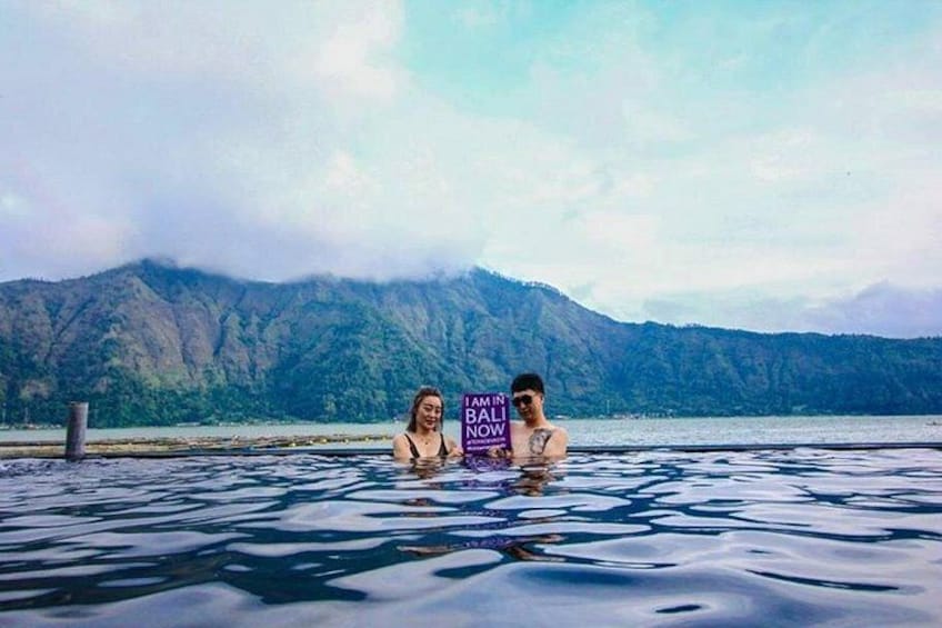 Two people in a large body of water with mountains in the background. 2