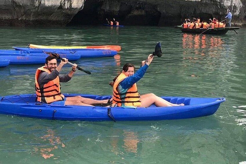 Dos personas remando en kayak en un lago tranquilo, con otras canoas y gente al fondo. 3