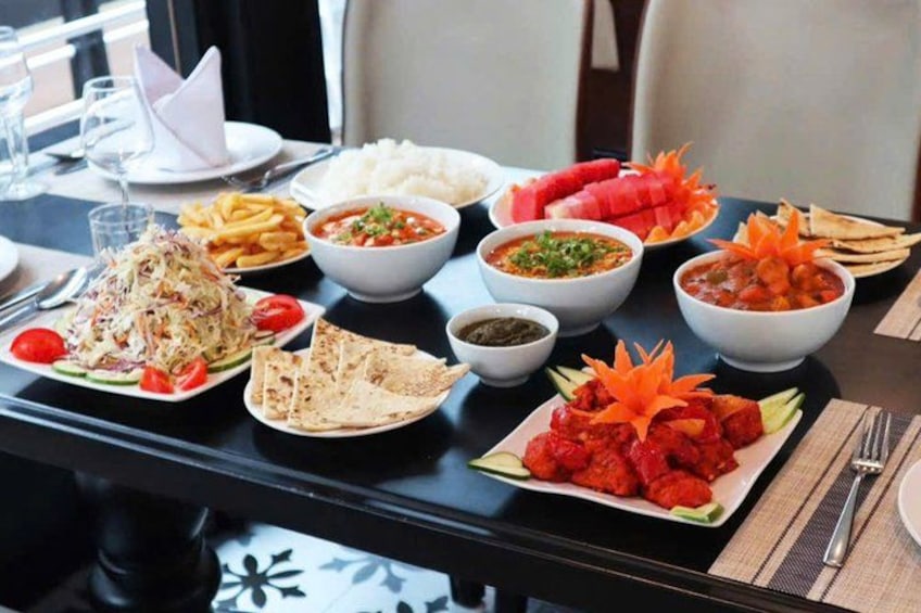 Una mesa con diversos platos, incluyendo arroz, papas fritas, una ensalada y un tazón de sopa. 3
