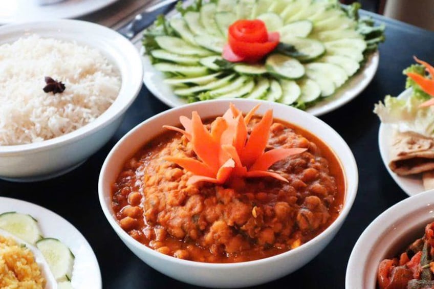 Variedad de platos, incluyendo un tazón de curry adornado con rodajas de zanahoria, arroz y una ensalada de pepino. 5