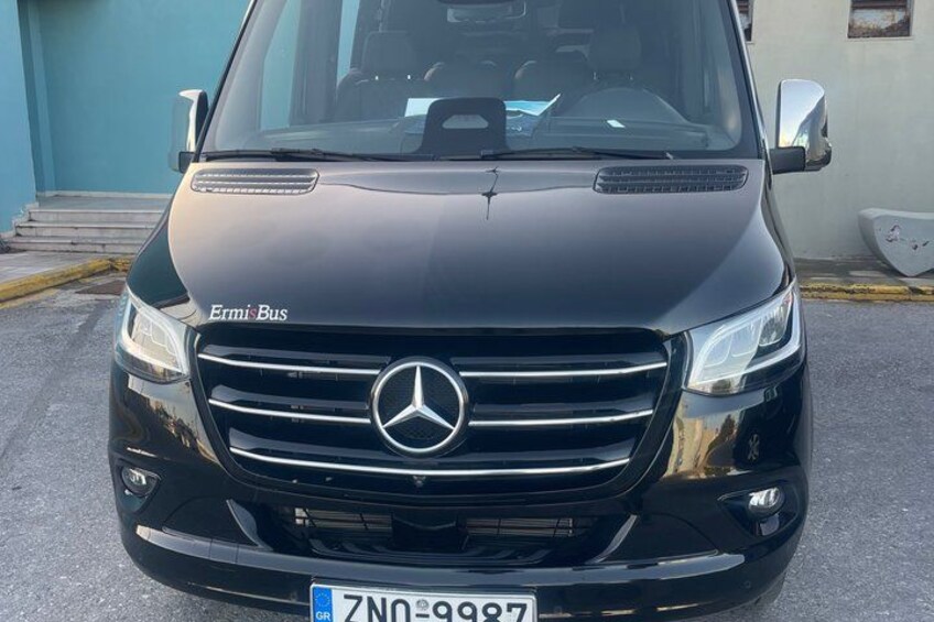 A black Mercedes-Benz Ermis Bus parked in front of a building. 3