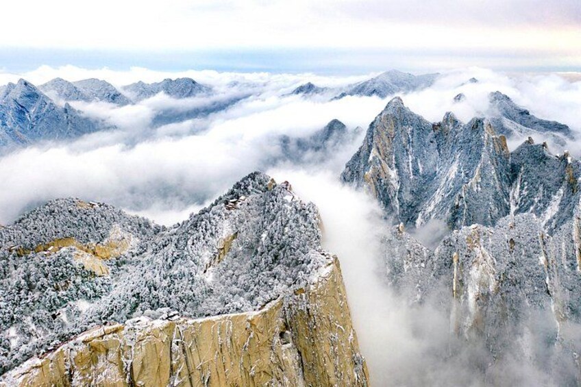 A snow-covered mountain range with sharp peaks and a valley below. 3