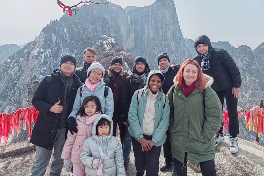 A group of people standing in front of a mountain with a red rope barrier. 1