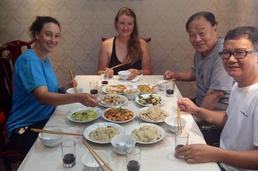 A group of people sitting around a table with various dishes and drinks. 2