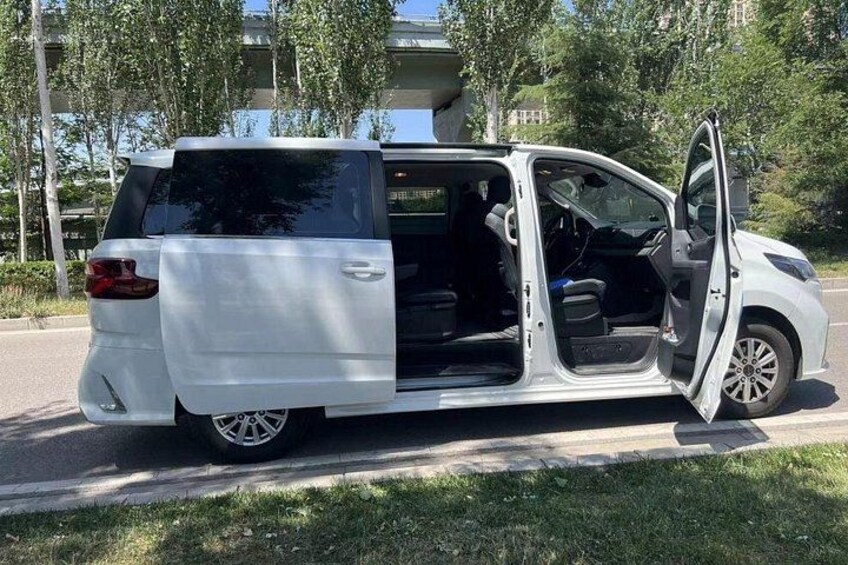 Una minivan blanca estacionada en una calle con la puerta abierta, mostrando el interior. 2