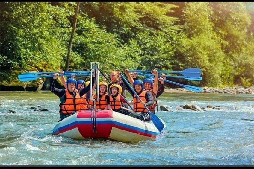 A group of people in a raft on a river surrounded by trees. 3
