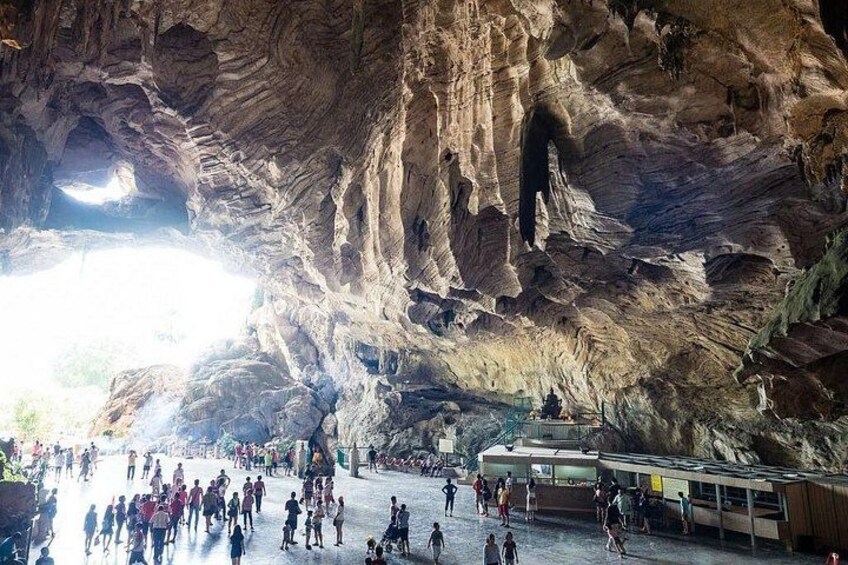 A cave with people walking inside, a bus, and a large opening at the top. 5