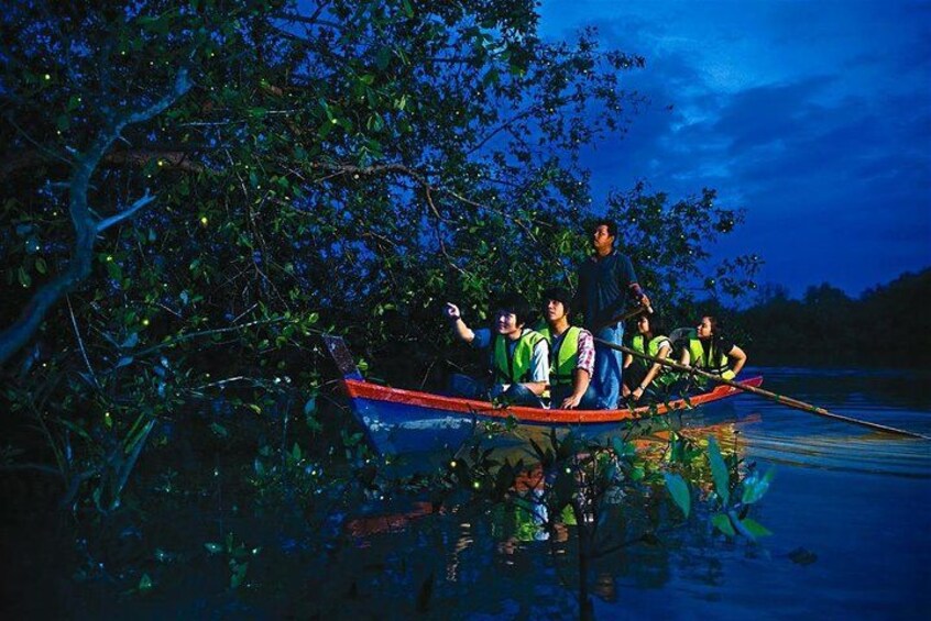A group of people in a canoe on a calm body of water at night, surrounded by trees. 3