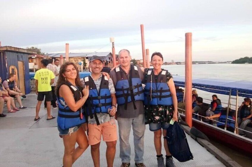 A group of people wearing life jackets on a dock by the water. 5