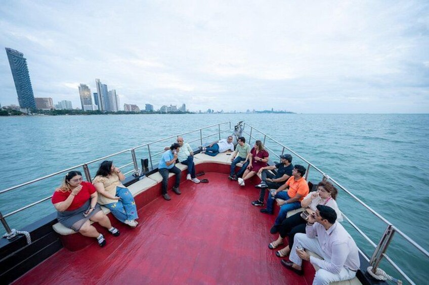 A group of people sitting on a boat with a city skyline in the background. 5