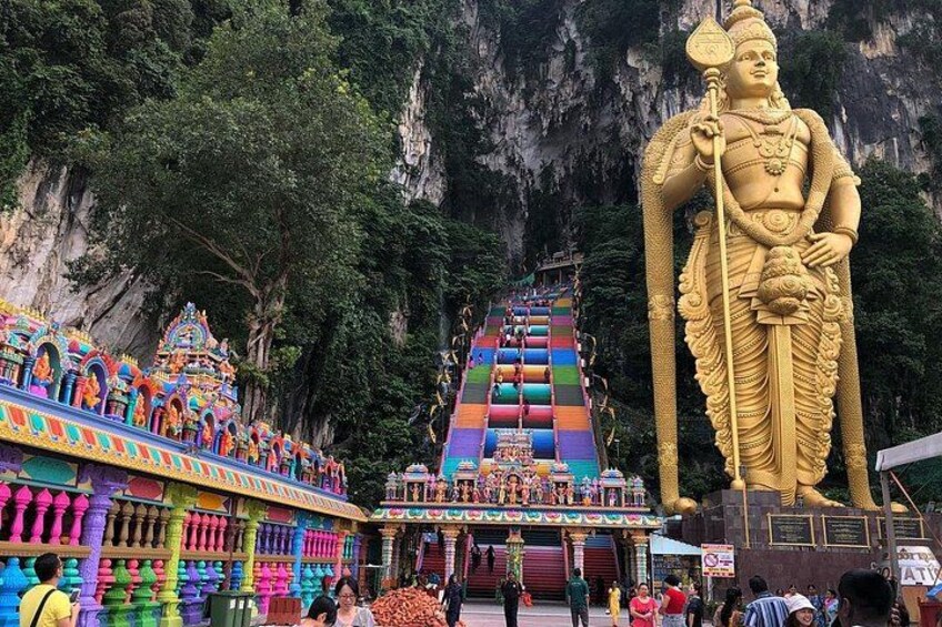 A large golden statue, colorful temple architecture, and a multi-tiered staircase. 1