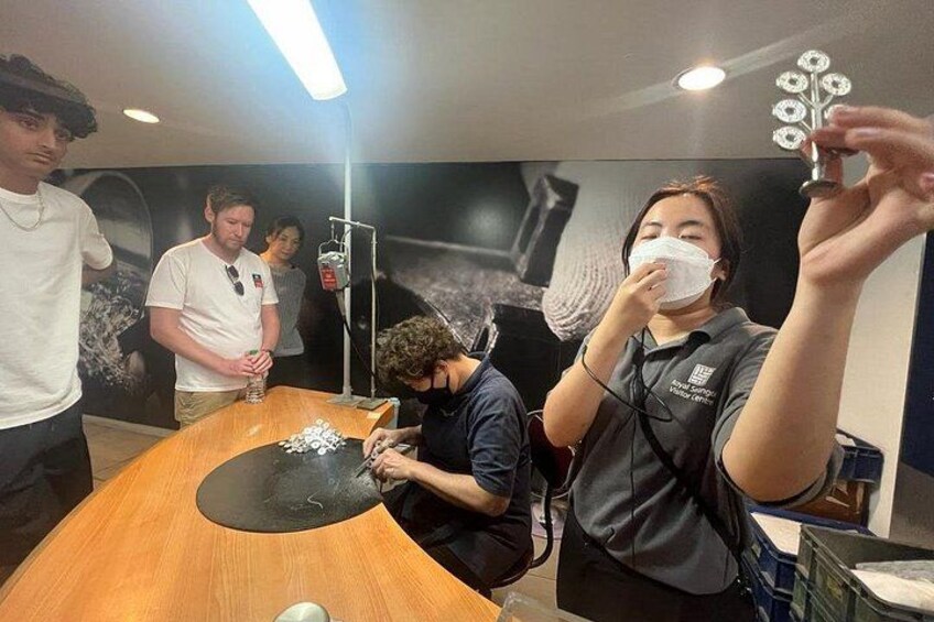 A person holding a decorative item, a table with a black mat, and a poster with a floral design in the background. 5