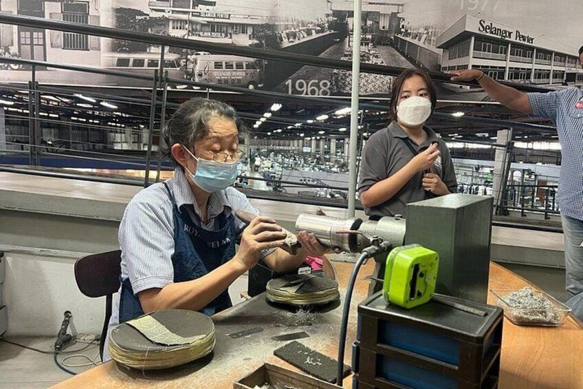 A person working with a machine in an industrial setting, with another person standing nearby. 3
