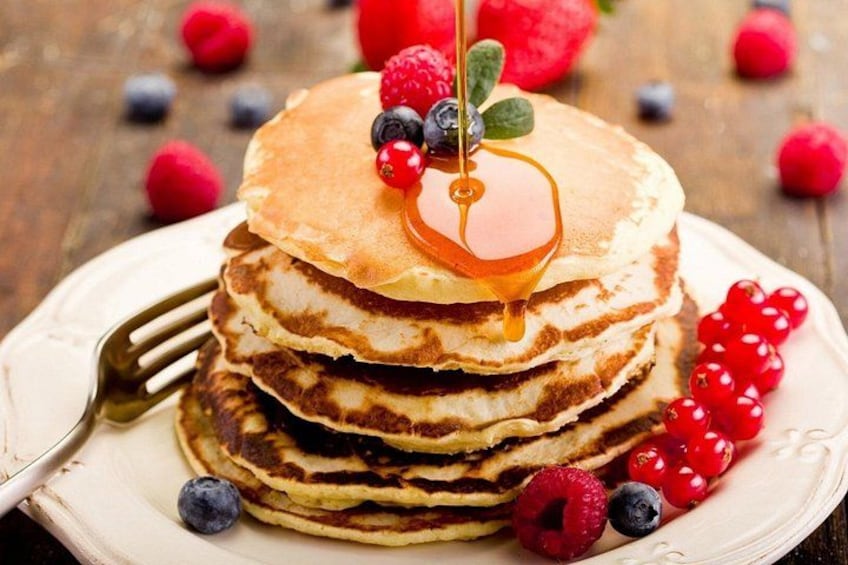 Une pile de crêpes arrosées de sirop et garnies de fruits rouges. 3