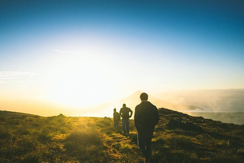 A group of people hiking on a grassy hill with a clear sky. 5