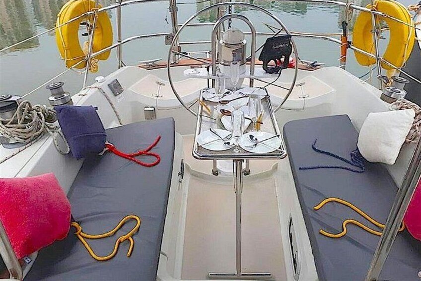 Le pont d’un bateau, avec deux espaces de sièges rembourrés, un volant et des bouées de sauvetage. 2